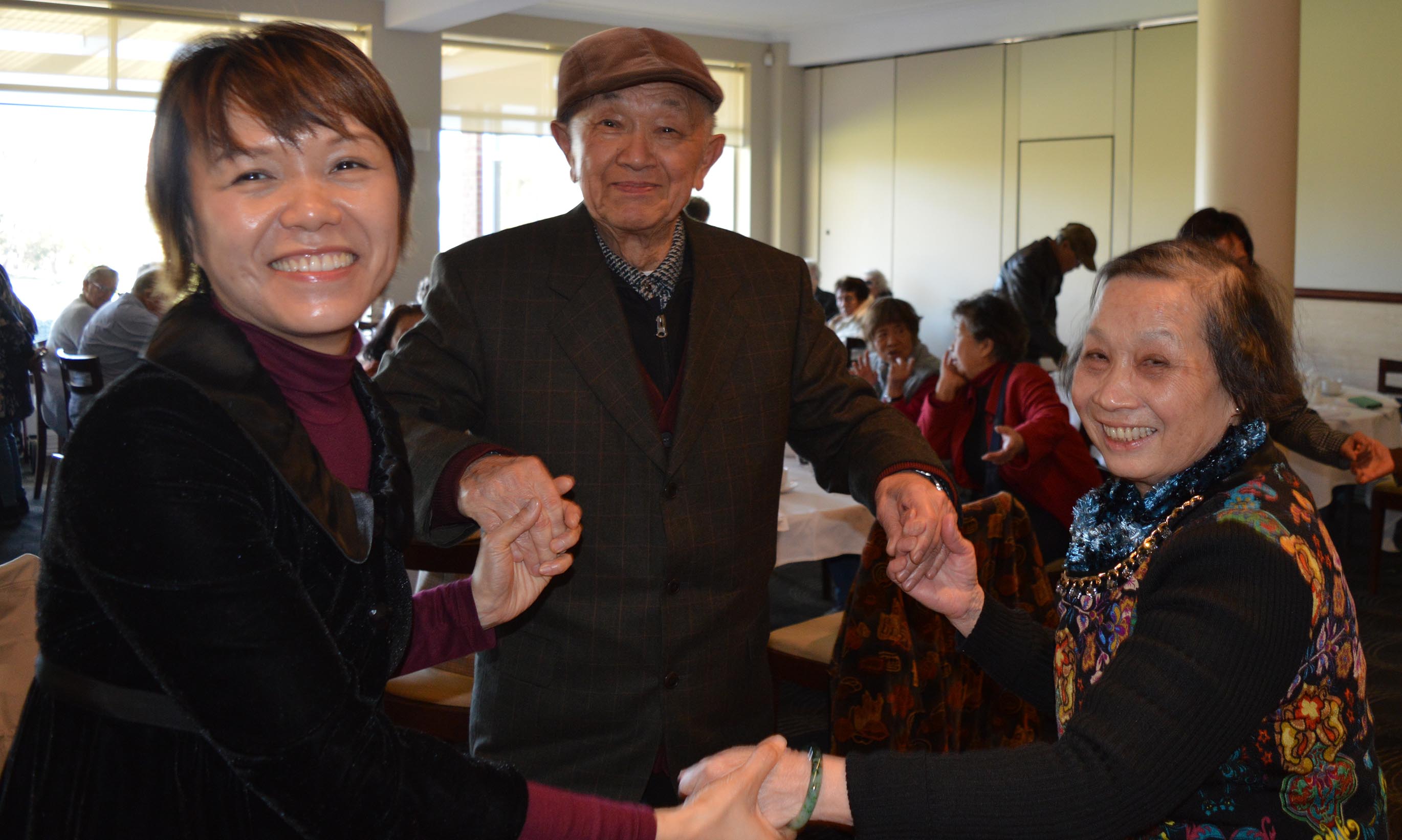 JNC staff member and two older people dancing at the Winter Lunch in June 2018